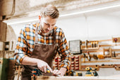 bearded carpenter holding chisel while carving wood workshop