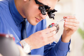 Engraver carves jewelry with the help of a microscope