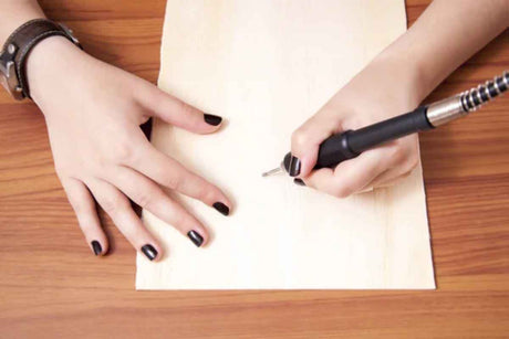Sketching on a wooden board with a pneumatic carving tool.