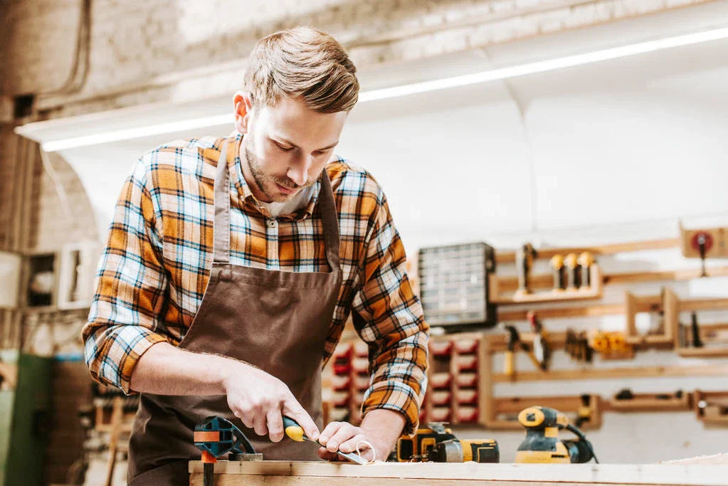 bearded carpenter holding chisel while carving wood workshop